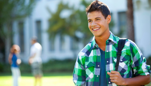 Student wearing backpack stands outside on a college campus